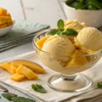 Homemade mango sorbet made with a Ninja Creami, served in a glass bowl with fresh mango slices and mint, showcasing a healthy frozen dessert option